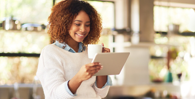 Woman drinking coffee and looking at tablet